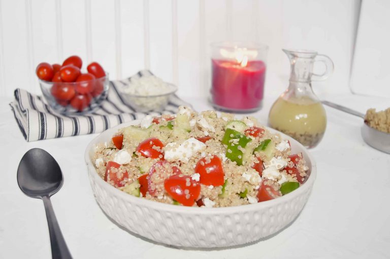 Quinoa Salad with Cucumber, Tomato and Feta with a bowl of tomatoes and a bowl of feta on a black and white towel, jar of Italian Dressing and candle. www.atwistedplate.com