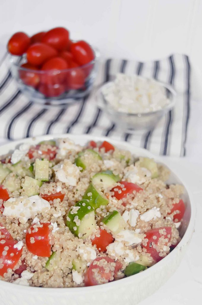 Quinoa Salad with Cucumber, Tomato  and Feta with a bowl of tomatoes and a bowl of feta on a black and white towel. www.atwistedplate.com