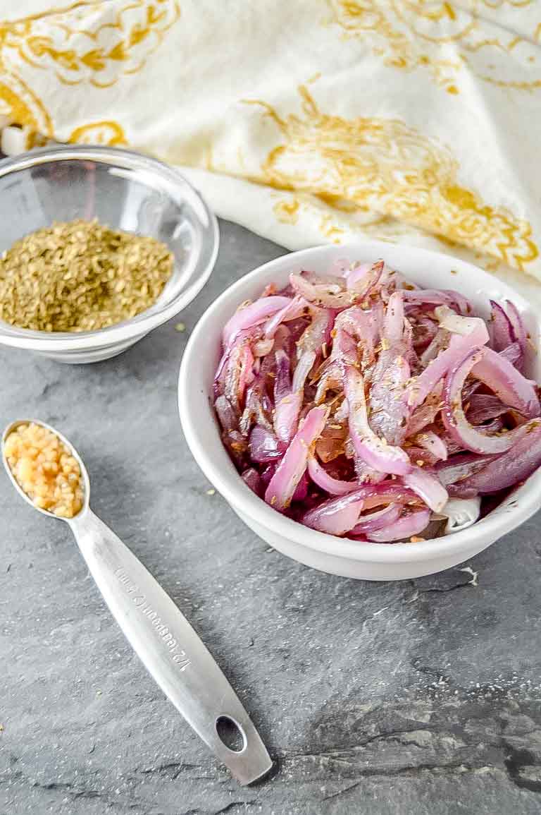 Perfectly Roasted Red Onion in bowl with minced garlic and oregano www.atwistedplate.com/perfectly-roasted-red-onions/
