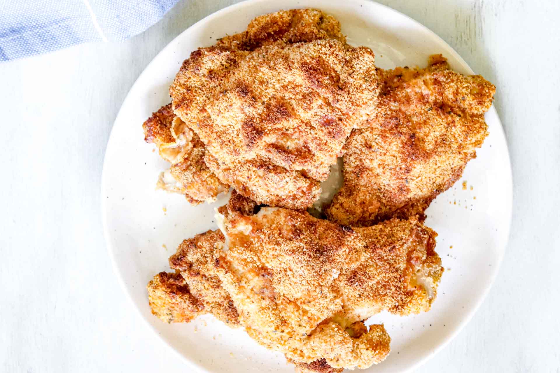 Image of Whole30 Air-fryer 5 chicken thighs on a round white plate. https://www.atwistedplate.com/whole30-air-fryer-chicken-thighs/